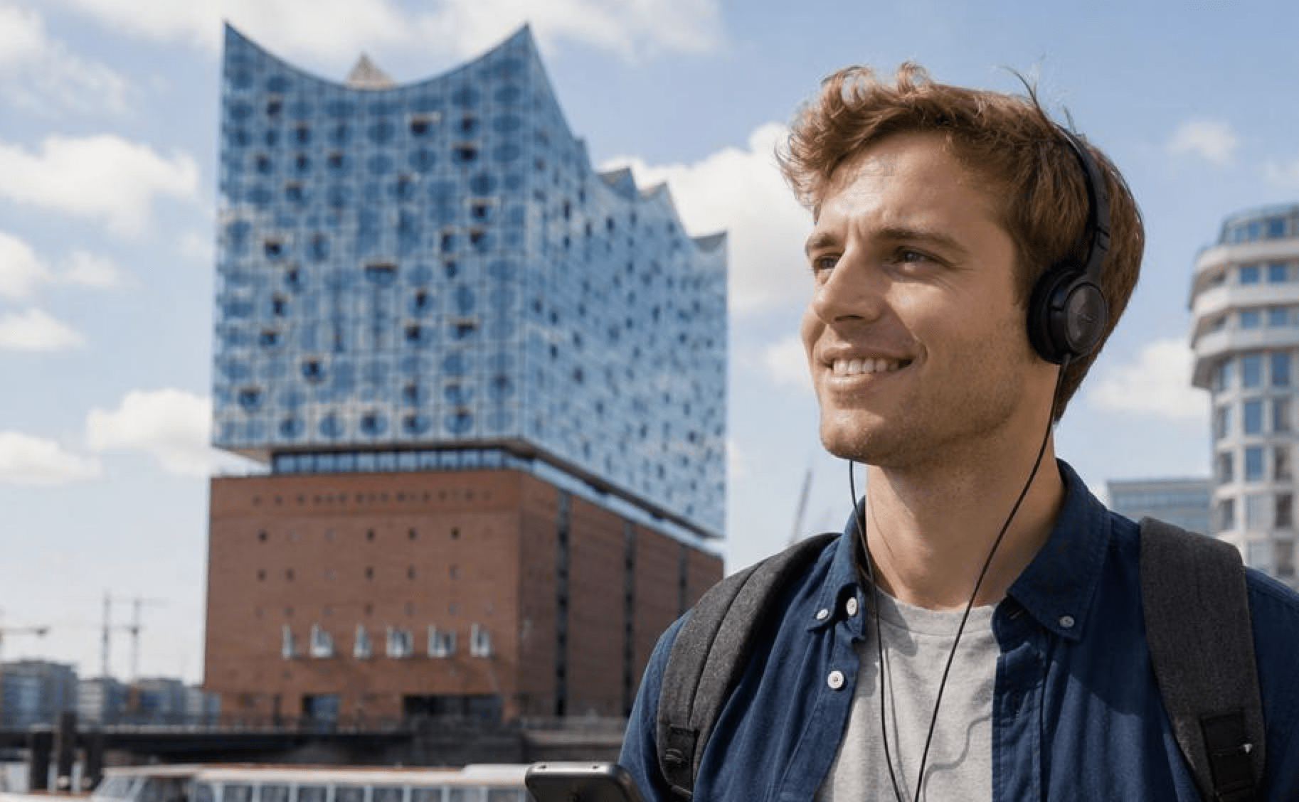 a happy man listening to an audio guide in hamburg